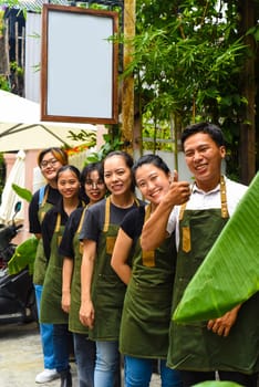 Vietnamese coffee shop team smiling and standing together against a cafe