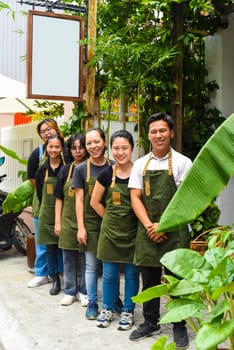 Vietnamese coffee shop team smiling and standing together against a cafe
