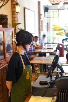 Young Vietnamese waitress serving a customer at the checkout in cafe.