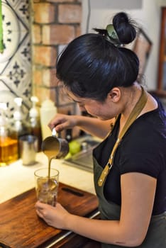 A young Vietnamese girl barista making coffee in a coffee house