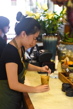 A young Vietnamese girl barista making coffee in a coffee house