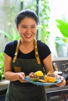 Vietnamese girl serving homemade ice cream with waffle at a coffee shop.