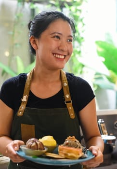 Vietnamese girl serving homemade ice cream with waffle at a coffee shop.