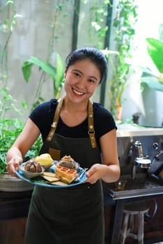 Vietnamese girl serving homemade ice cream with waffle at a coffee shop.