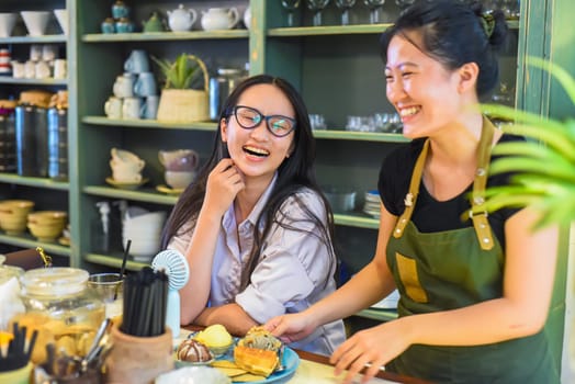 Smiling Vietnamese waitress serving a customer ice cream with waffle in Vietnamese coffee shop