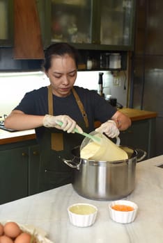 Vietnamese woman mixing dough for a home made cheese cake