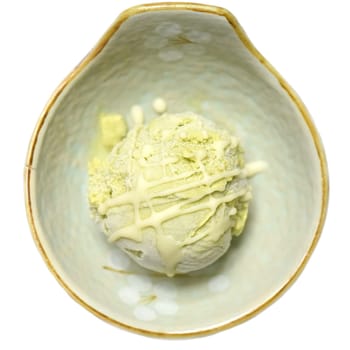Scoop of homemade avocado ice cream in a ceramic bowl isolated on white background