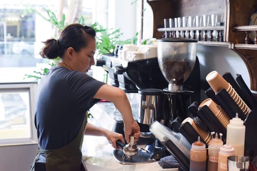 Vietnamese barista making espresso with coffee machine close up