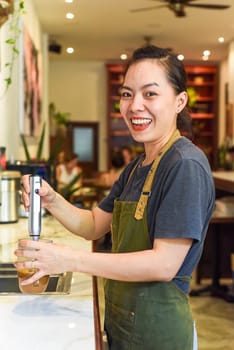Vietnamese barista using a mixer for condensed milk in glass cup for preparing vietnamese coffee Cafe Sua