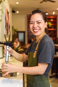 Vietnamese barista using a mixer for condensed milk in glass cup for preparing vietnamese coffee Cafe Sua