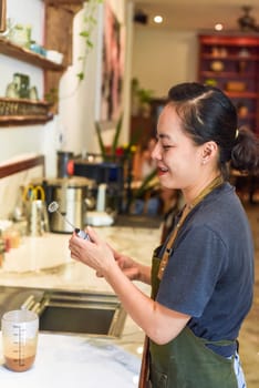 Vietnamese barista holding a mixer for condensed milk in glass cup for preparing vietnamese coffee Cafe Sua