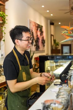 Vietnamese waiter working in counter with cashier machine in a cafe