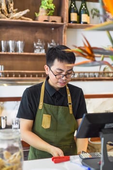 Vietnamese waiter working in counter with cashier machine in a cafe