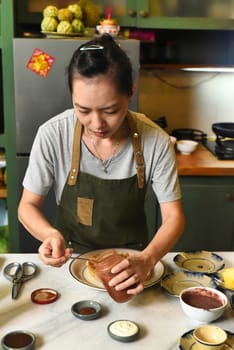 Vietnamese woman in apron serving foor on the table