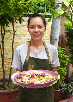 Vietnamese woman waitress serving pan fried chicken with vegetables in outdoor cafe