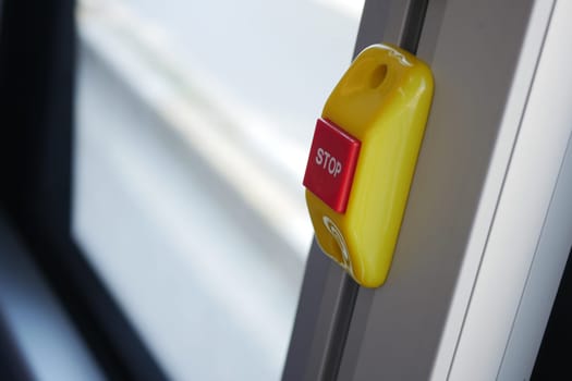 Bright yellow stop button located on the bus window for passengers.