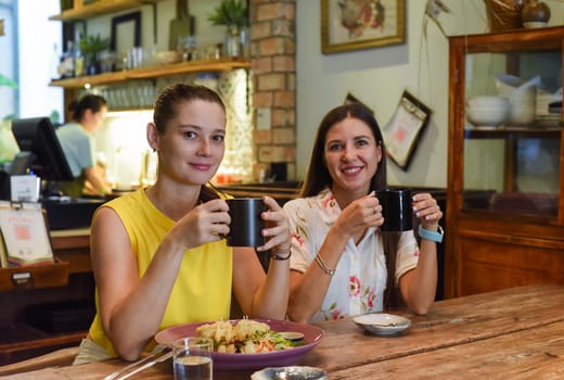 Two best friends talking and eating in a cafe
