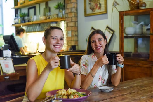 Two best friends talking and eating in a cafe