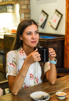 Portrait of smiling russian woman drinking hot capuccino and looking right