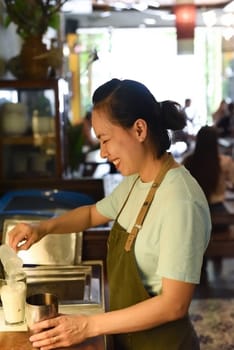 Vietnamese barista using a mixer for condensed milk in glass cup for preparing vietnamese coffee Cafe Sua
