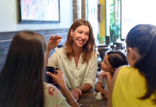 Female best friends talking and eating in a cafe