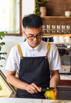 Vietnamese man chef peeling fresh mango in cafe