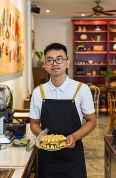 Vietnamese man chef in uniform holding fresh baked belgian waffles with chicken, cheese and vegetables