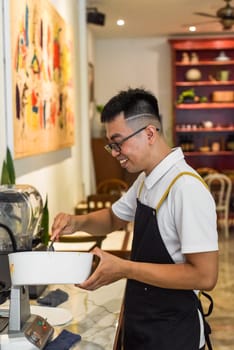 Vietnamese man chef in uniform holding spoon and bowl with liquid dough for belgian waffles
