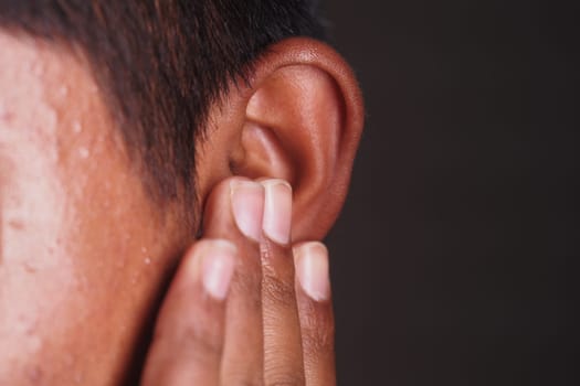 A person is gently holding their ear with fingers, focused and attentive.