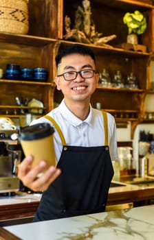 Vietnamese smiling waiter holding paper cups with coffee in a cafe