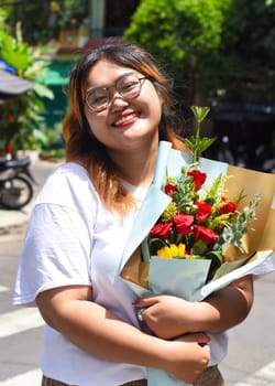 Happy vietnamese beatiful woman holding bouquet of flowers