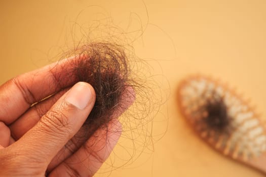 Individual holds a clump of hair removed from a hairbrush at home.