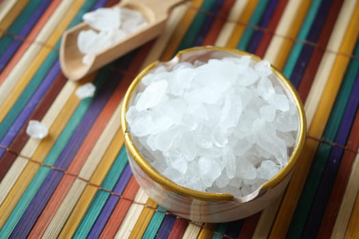 Clear salt crystals are displayed in a bowl on a vibrant mat.