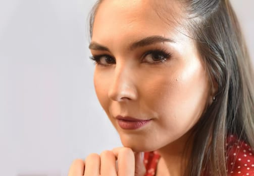 Portrait of young woman with make up against light background close up