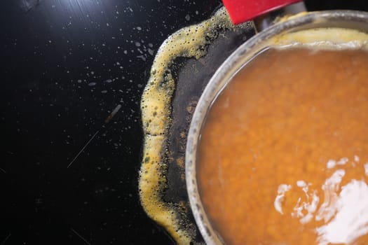 Closeup of burnt oil bubbling in a pan, leaving residue buildup on the stoves surface