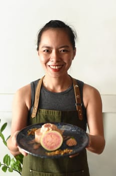 Vietnamese waitress smiles and holding plate of guava cake
