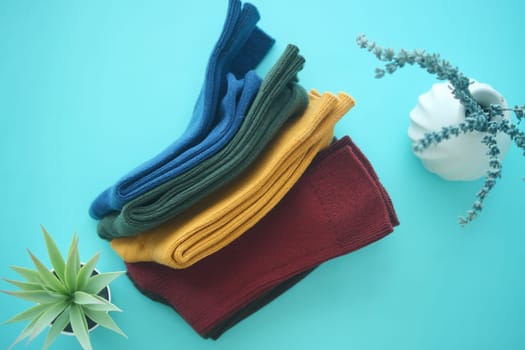 A neat stack of folded socks in various colors sits on a bright blue tabletop.
