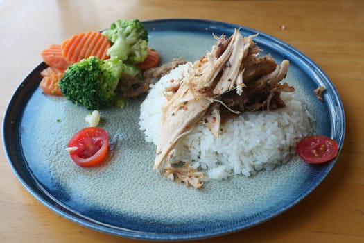 A well-presented dish featuring rice, shredded chicken, and vegetables.