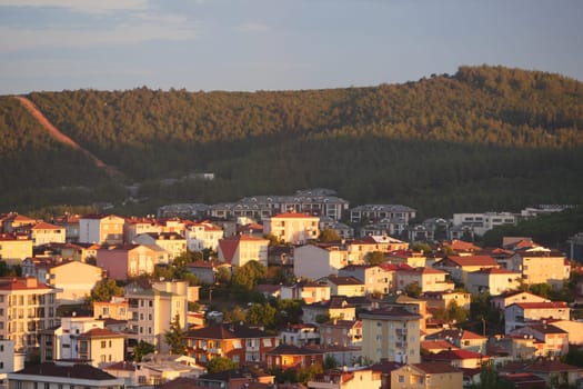 Residential buildings bask in golden sunlight with hills in the background.