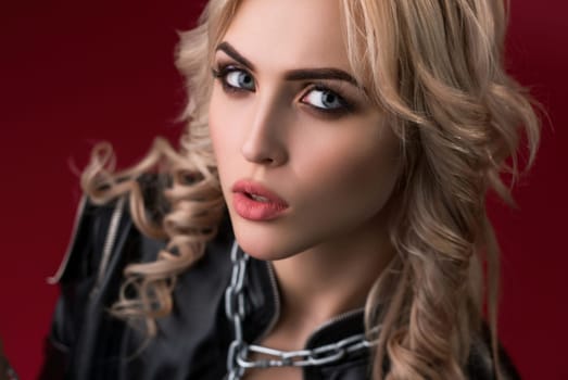 Sexy blonde with locks and chain on her neck wearing black leather jacket portrait