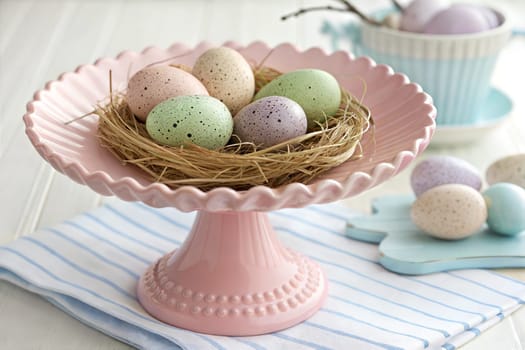 A pastel colorful speckled eggs on a pink cake stand. Spring celebrations and holiday decor. Easter concept.