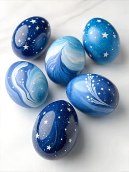 A beautifully painted set of glossy Easter eggs in shades of blue, decorated with starry patterns and galaxy-inspired swirls, perfect for Easter celebrations.