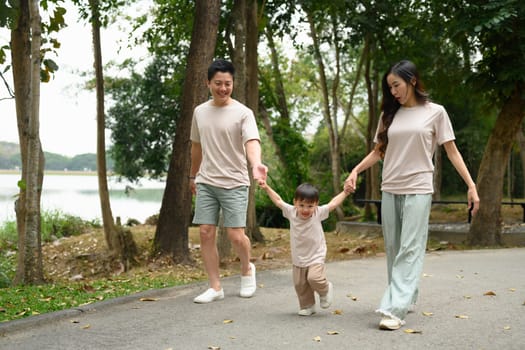 Happy family walking together along a park path, holding hands.