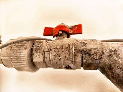 Dust-covered pipes and a rusty valve highlight the neglect in an abandoned industrial space, reflecting years of inactivity and decay.