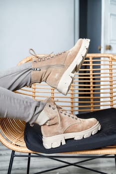 Model showcases stylish boots while lounging on a cozy chair in a contemporary indoor space, highlighting fashion trends.