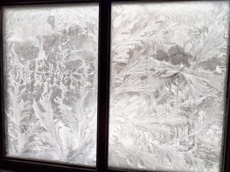 Delicate and intricate snow patterns cover the glass, showcasing nature's artistry on a frigid winter morning.