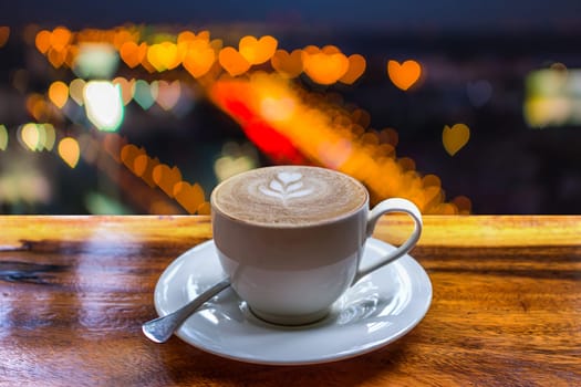 Coffee in white cup on wood table and Love abstract bokeh background heart shape of light for celebration valentine's day and wedding anniversary