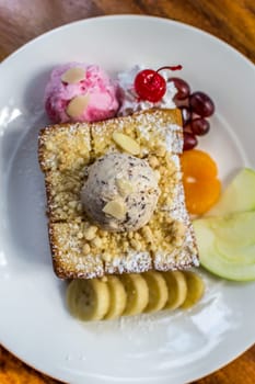 Honey toast with icecream and fruit topped with chocolate syrup and honey is a dessert tasty sweet