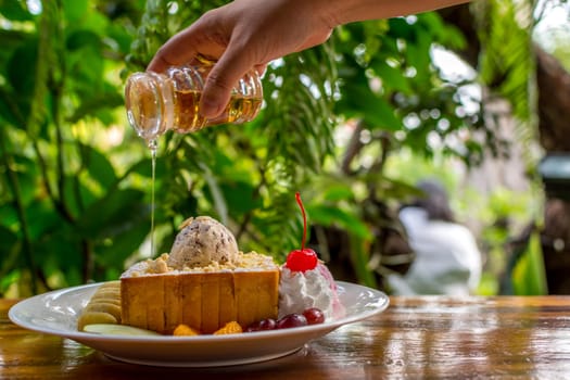 Honey toast with icecream and fruit topped with chocolate syrup and honey is a dessert tasty sweet