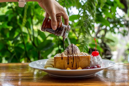 Honey toast with icecream and fruit topped with chocolate syrup and honey is a dessert tasty sweet